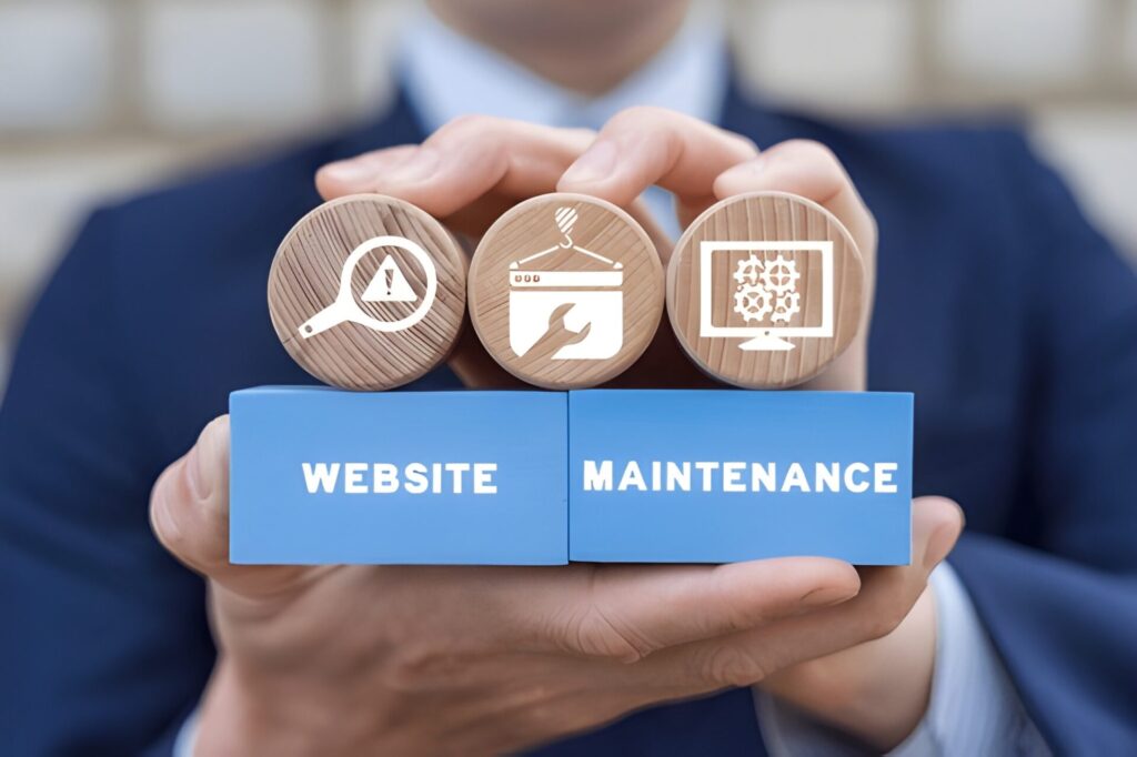 Hands holding wooden blocks labelled website maintenance