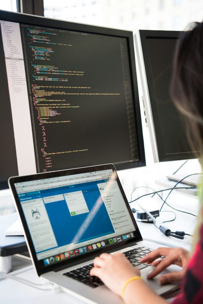 Person designing and developing a website, working with code on a desktop computer